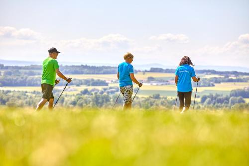 three people walking on a hill with poles at Parkhotel Bad Griesbach in Bad Griesbach