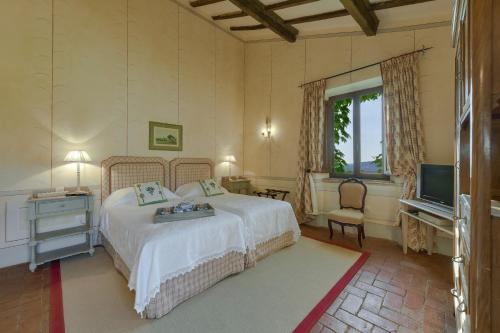 Un dormitorio con una cama y un televisor. en La Marrana - Castello del Terriccio, en Castellina Marittima