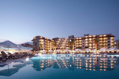 a hotel pool with chairs and umbrellas at night at Green Garden Resort & Spa Hotel in Alanya