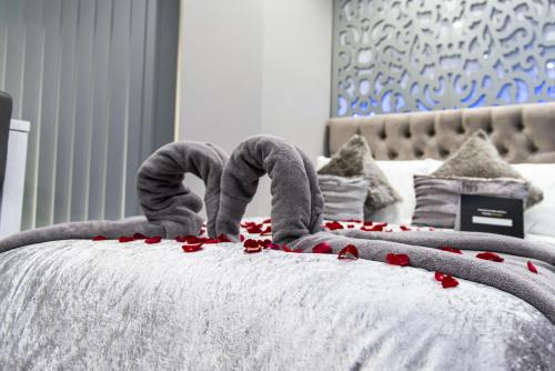 a bed with red rose petals on it at Aphrodite Suites in Bradford