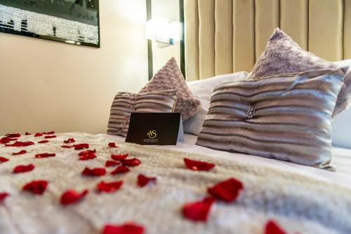 a bed with red flowers on it with a laptop on it at Aphrodite Suites in Bradford