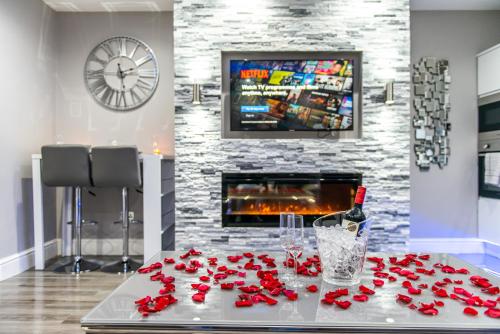 a table with roses and a bottle of wine and a fireplace at Aphrodite Suites in Bradford
