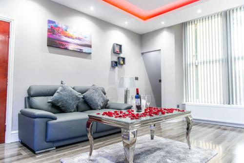 a living room with a couch and a table with roses on it at Aphrodite Suites in Bradford