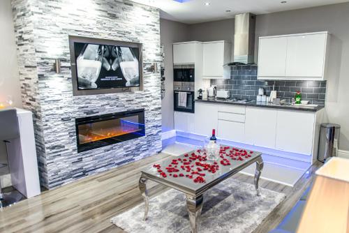 a living room with a fireplace and a table with roses on it at Aphrodite Suites in Bradford