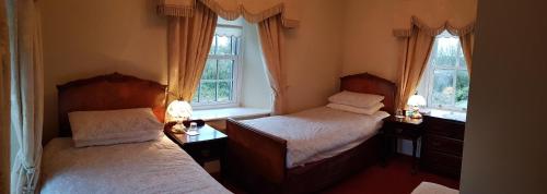 two beds in a room with two windows at The Harbour Masters House in Banagher