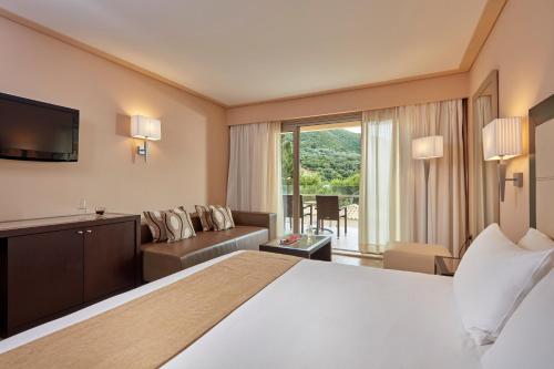 
a hotel room with a large bed and a large window at Atlantica Grand Mediterraneo Resort - Adults Only in Kompítsion
