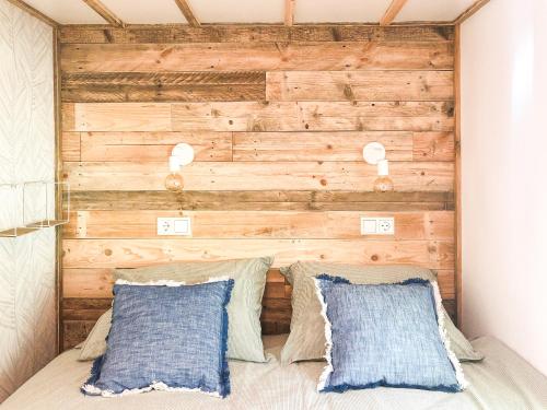 1 dormitorio con pared de madera detrás de una cama con almohadas en STOERbuiten lodge Les Charmes en Pech Sec