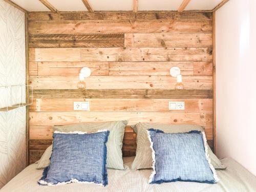 - une chambre avec un mur en bois derrière un lit et des oreillers dans l'établissement STOERbuiten lodge Les Charmes, à Pech Sec