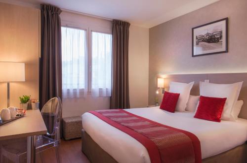 a hotel room with a large bed with red pillows at Dièse Hôtel Bastille in Paris