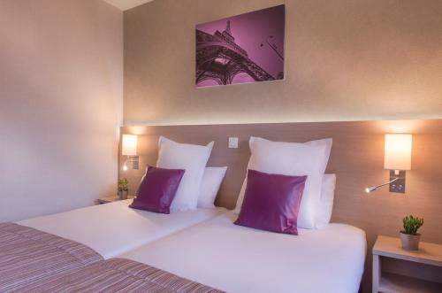 a bedroom with two beds with purple and white pillows at Dièse Hôtel Bastille in Paris