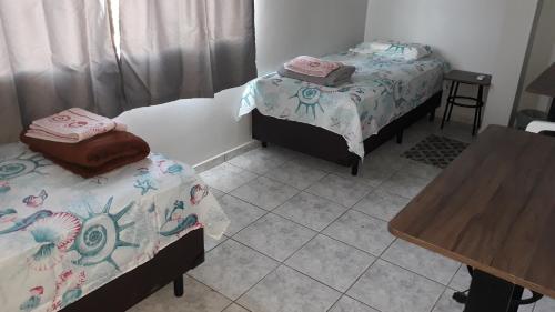 a room with two beds and a wooden table at Edifício Belio in Cascavel