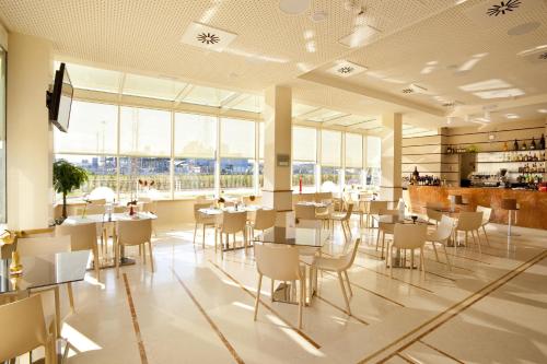 a restaurant with white tables and chairs and windows at Breaking Business Hotel in Mosciano SantʼAngelo