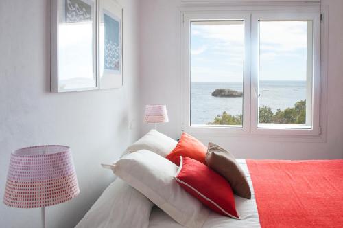 Schlafzimmer mit einem Bett mit roten und weißen Kissen in der Unterkunft Apartamento Ferrera Park 505 in Cala Ferrera