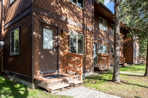 a log cabin with a front door and a tree at Huckleberry House in West Yellowstone