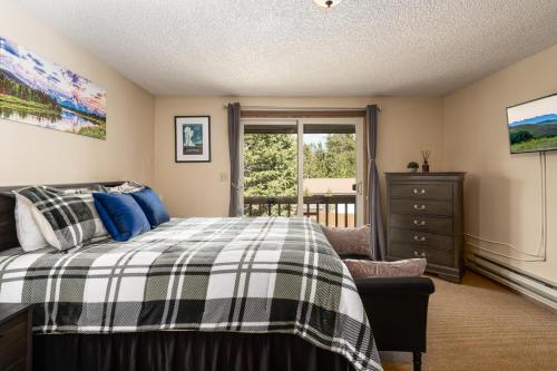 a bedroom with a bed and a dresser and a window at Huckleberry House in West Yellowstone