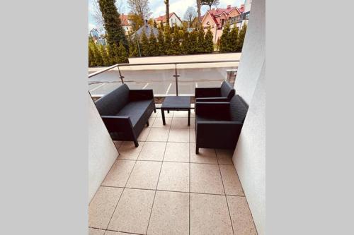 a balcony with couches and a table on a building at REWAL Komfortowy apartament przy plaży typu STUDIO in Rewal