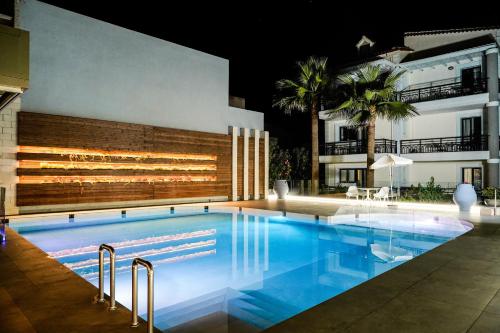 a swimming pool in front of a building at night at Alkionides Seaside Hotel in Plataniás