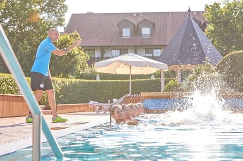 a man standing in a pool with a girl in the water at Parkhotel Bad Griesbach in Bad Griesbach
