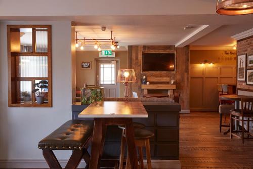 een restaurant met een bar met een tafel en stoelen bij The Churchill By Greene King Inns in Royal Wootton Bassett