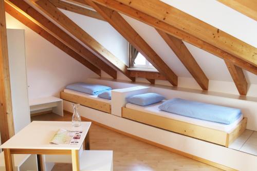 two beds in a attic room with a table at Manzoni Rooms in Merano