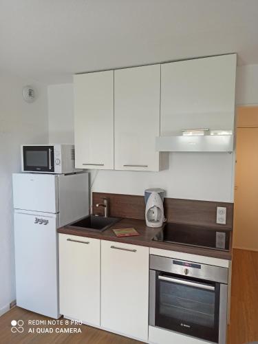 a small kitchen with white cabinets and a microwave at MON CABOURG PLAGE in Cabourg