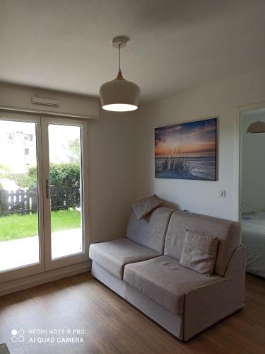 a living room with a couch and a sliding glass door at MON CABOURG PLAGE in Cabourg