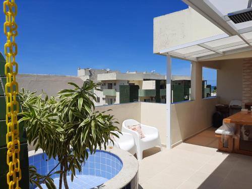 a balcony with a white chair and a table and a plant at Cobertura Duplex Na Praia Dos Milionários in Ilhéus