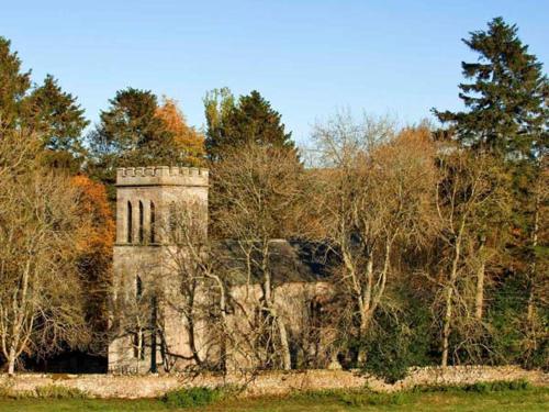 an old stone building in the middle of trees at Greystead Old Church in Hexham