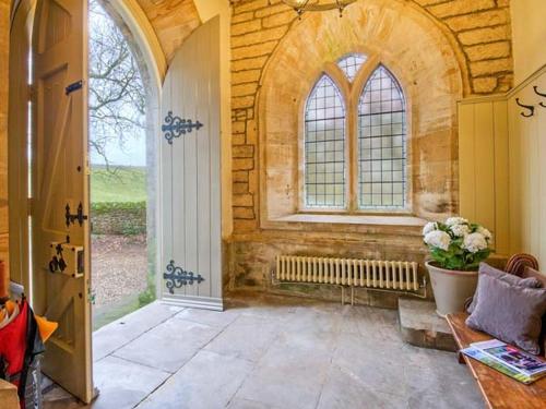 a room with a door and a window and a vase of flowers at Greystead Old Church in Hexham