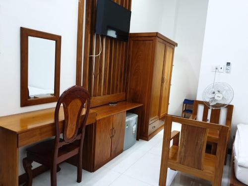 hotel đăng khôi 2 في تشاو دوك: مكتب خشبي مع مرآة وتلفزيون في الغرفة