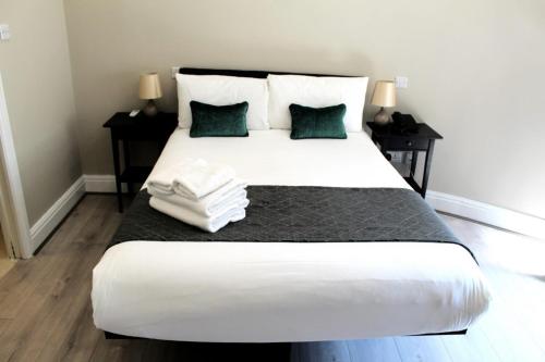 a bedroom with a large white bed with green pillows at Luxury Stay Rosebank Johannesburg in Johannesburg