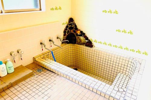 a tiled bathroom with a stuffed dog sitting on the wall at Manyi's Onsen House 天然温泉マンイの湯 in Shiraoi
