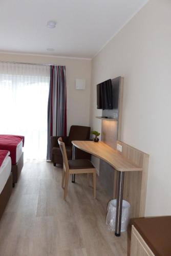 Habitación de hotel con escritorio y habitación con cama en Ladiges Gasthof en Holm