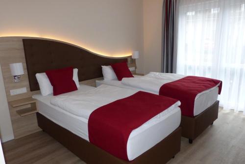 two beds in a hotel room with red pillows at Ladiges Gasthof in Holm
