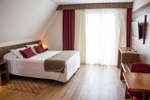 a hotel room with a bed and a window at Hotel Fioreze Centro in Gramado