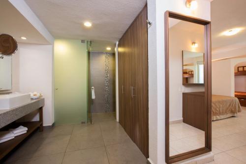 ein Bad mit einer Dusche, einem Waschbecken und einem Spiegel in der Unterkunft Crown Paradise Club All Inclusive in Puerto Vallarta