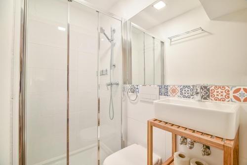 a white bathroom with a shower and a sink at Elevator's Beach House in Albufeira