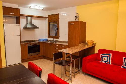 una cucina con divano rosso e sedia rossa di Apartments Ca la Victoria a La Vilella Baixa