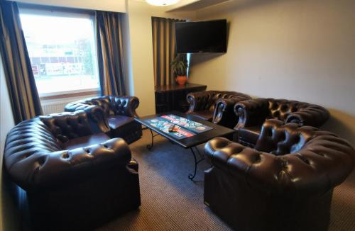 a living room with leather chairs and a table at Hotelli Iisoppi in Nokia