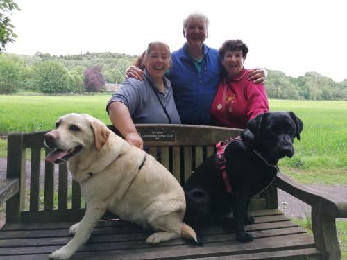 un grupo de personas sentadas en un banco con un perro en Broomfield House Bed and Breakfast, en Earlston