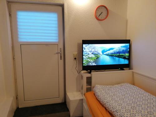 ein Schlafzimmer mit einem TV, einem Bett und einer Uhr in der Unterkunft Jasmin in Laichingen