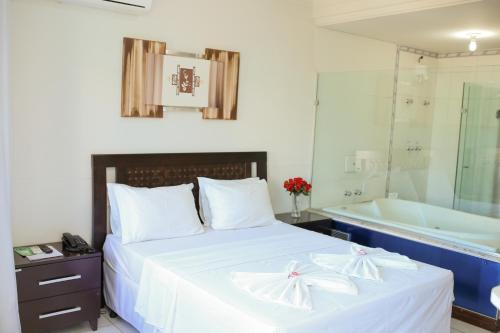 a bedroom with a bed and a bath tub and a sink at Palace Hotel in Araguari