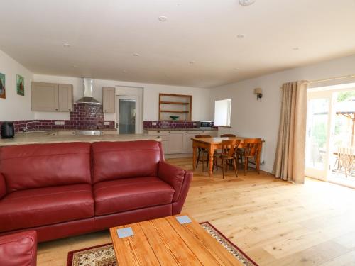 a living room with a red couch and a kitchen at Waveney View Cottage in Great Yarmouth