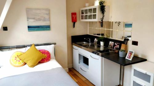 a small kitchen with a bed, stove, microwave and refrigerator at White's Row Resident in London