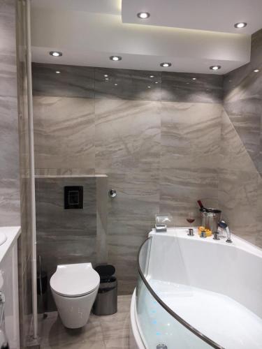a bathroom with a tub and a toilet and a sink at Apartment De Luna Belgrade in Belgrade