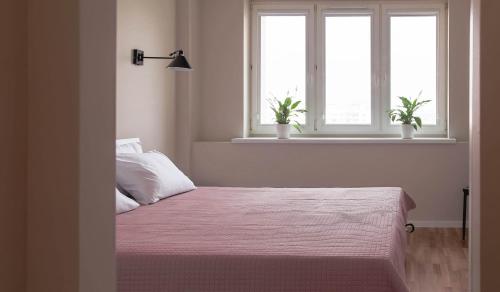 a bedroom with two windows and a bed with pink sheets at Dziesiąte Piętro in Poznań