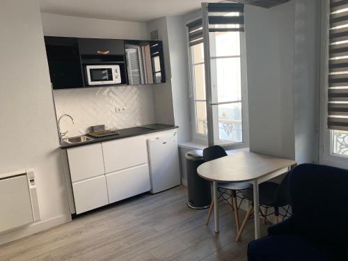 a small kitchen with a table and a table and chairs at L'annexe in Compiègne