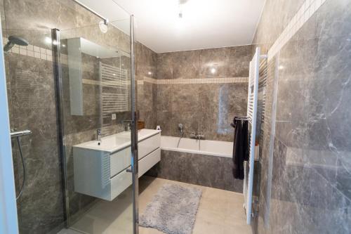 La salle de bains est pourvue d'une baignoire, d'un lavabo et d'une douche. dans l'établissement Brenda's Stay - Relax Appartement, à Bredene