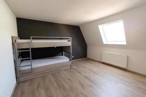 Cette petite chambre comprend des lits superposés et une fenêtre. dans l'établissement Brenda's Stay - Relax Appartement, à Bredene