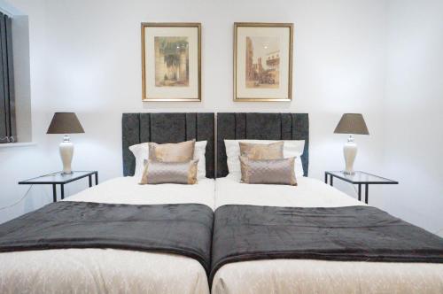a bedroom with a large bed with two tables at Premium Apartments Thatcham Broadway in Thatcham